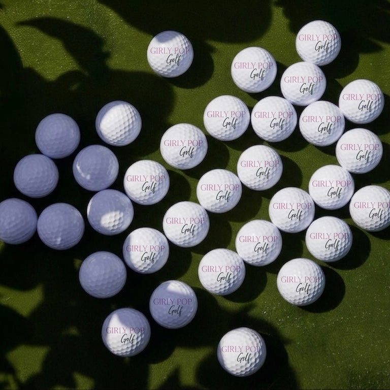Girly Pop Golf branded range balls on cut grass under the lights.