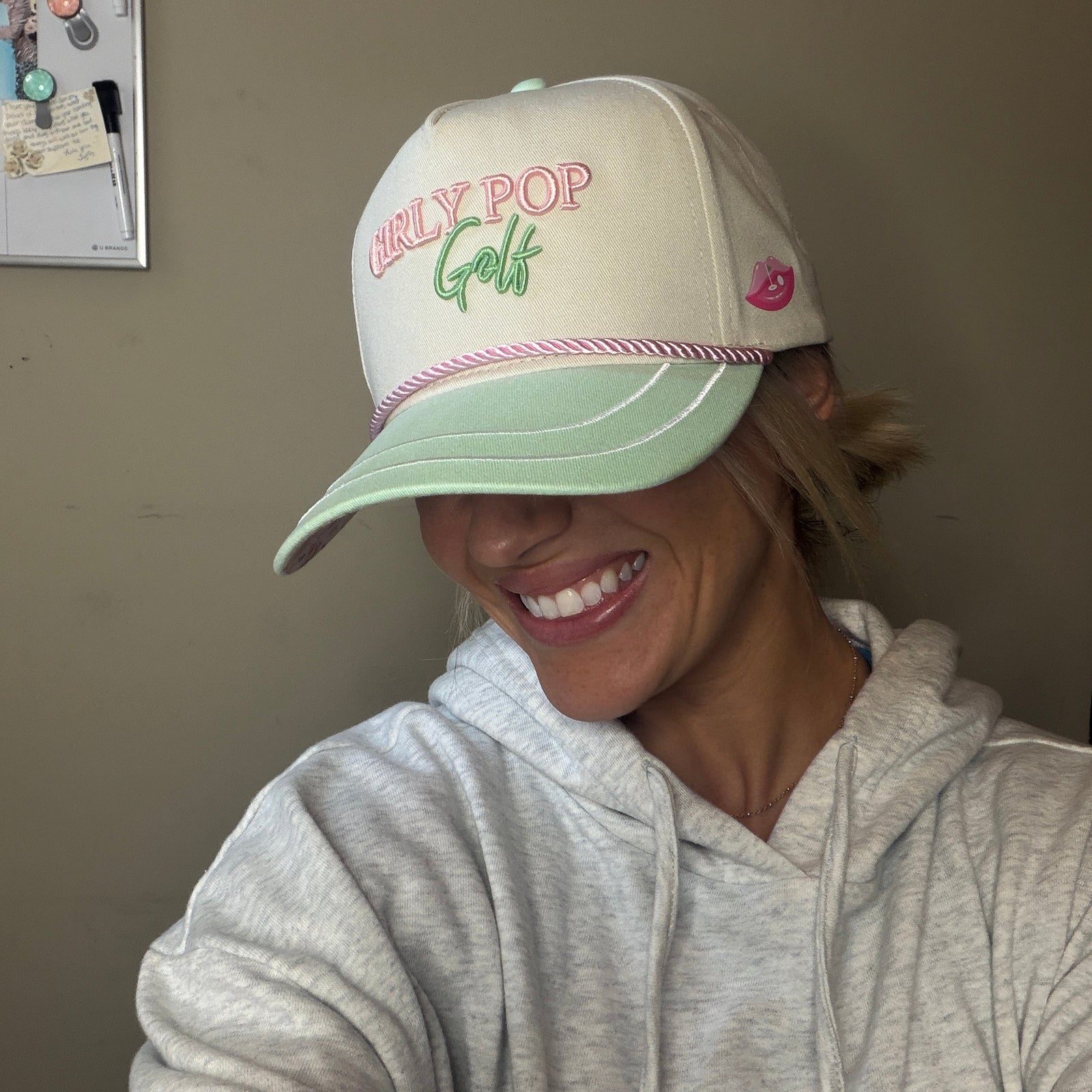 A member laughing in a cream Girly Pop Golf cap.